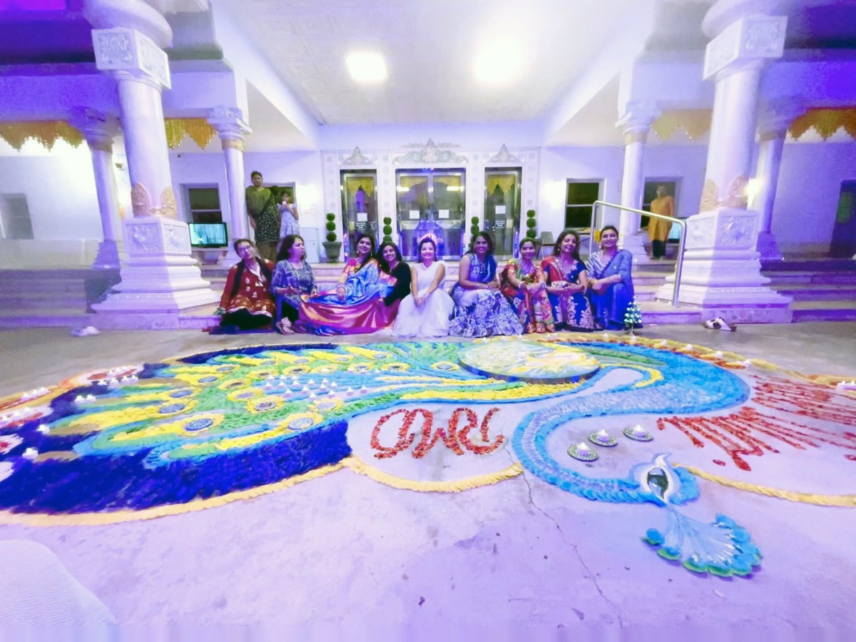 Group celebrating beside the completed Diwali Rangoli
